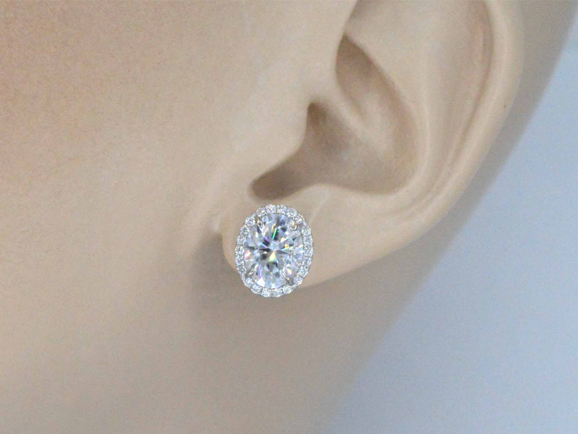 Witgouden entourage oorbellen met diamanten en een gemaakte ovale briljant