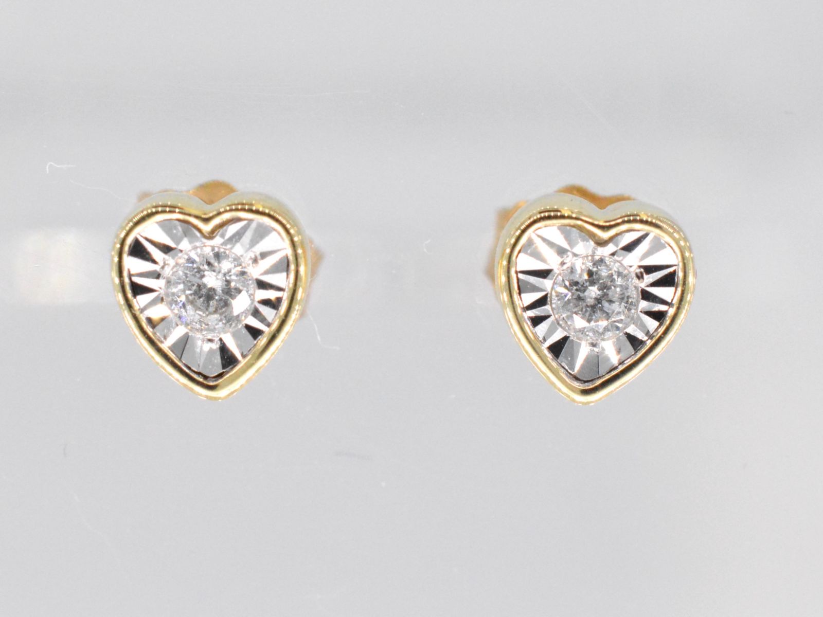 Gouden oorbellen met een briljant geslepen diamant in hartvorm