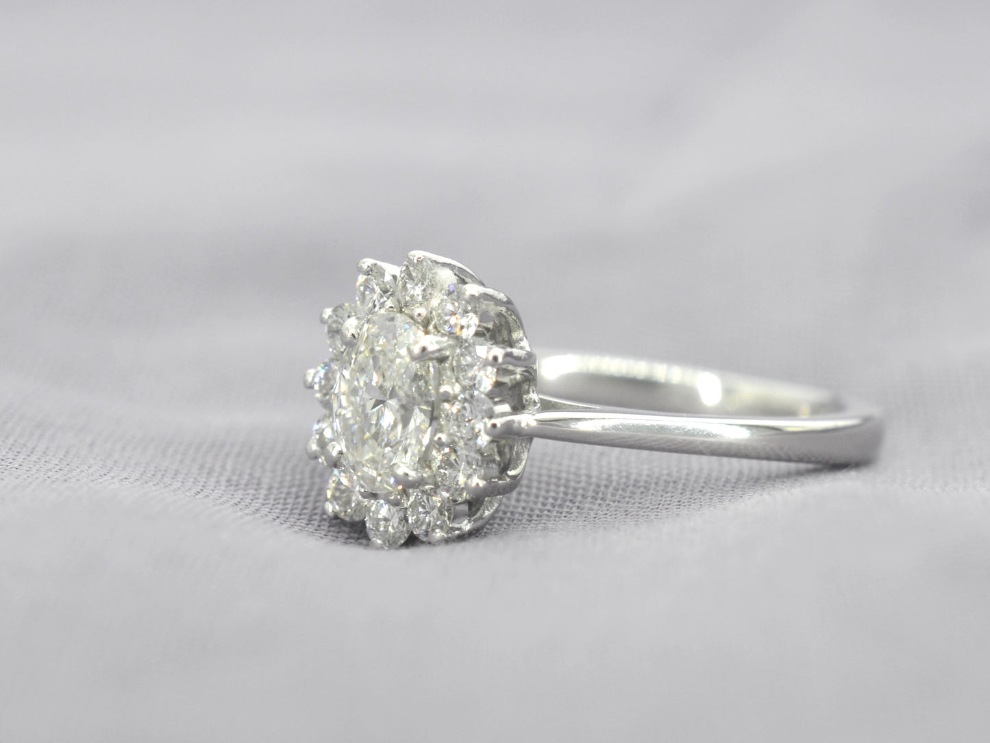 Platina entourage ring met een ovale diamant