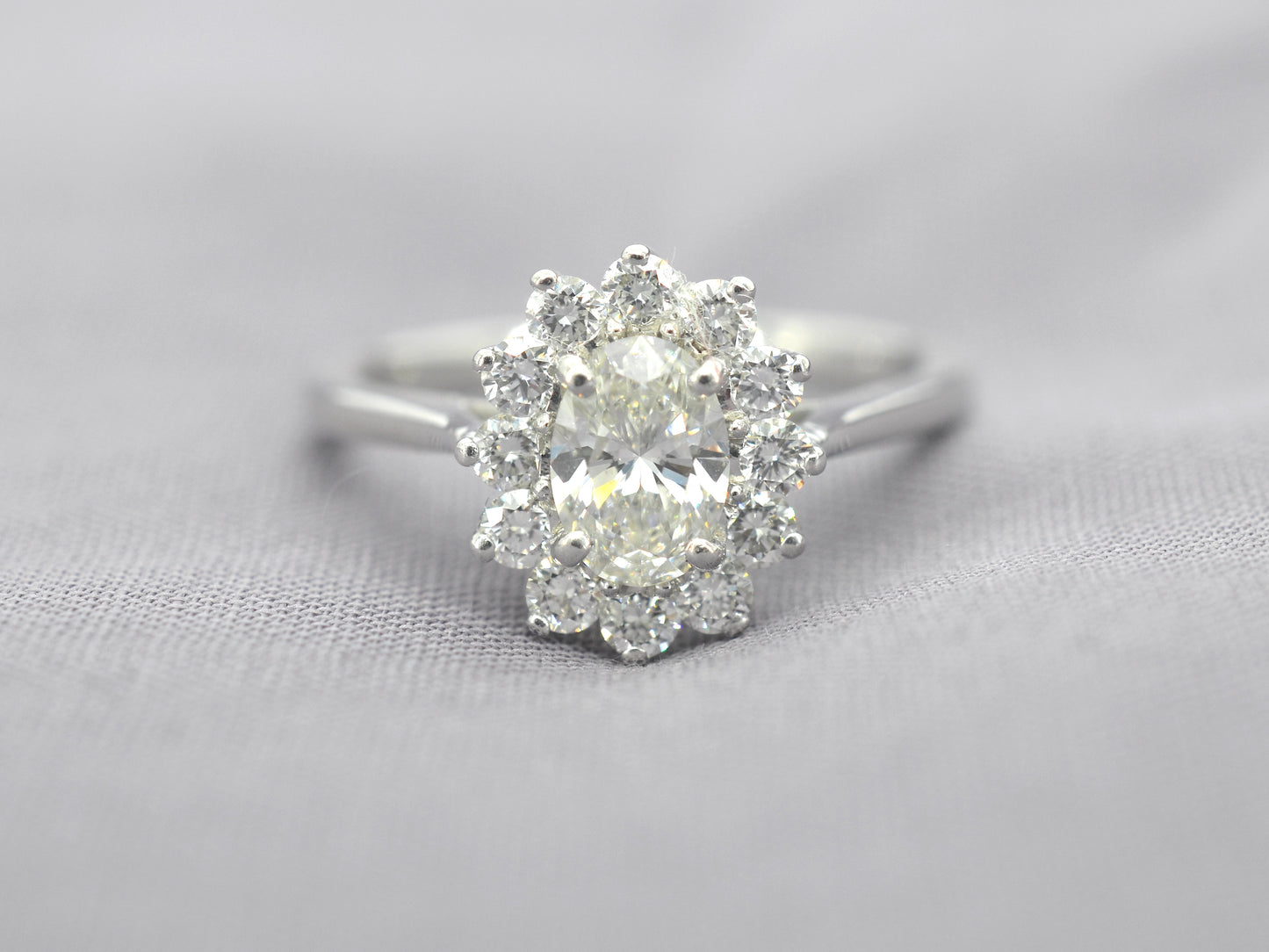 Platina entourage ring met een ovale diamant